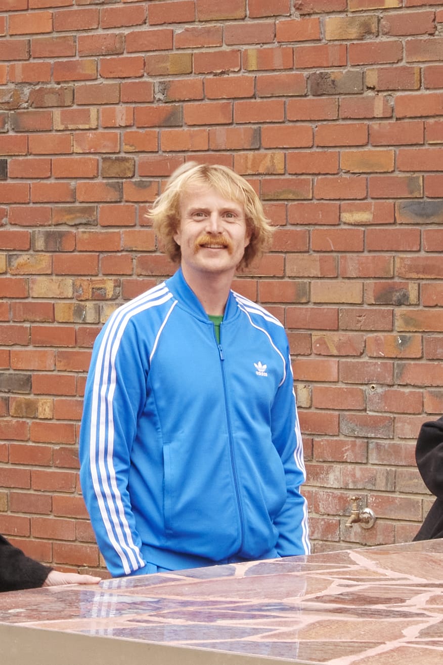 Ross Harding, founder of Finding Infinity, photographed standing and smiling, wearing a blue track top.