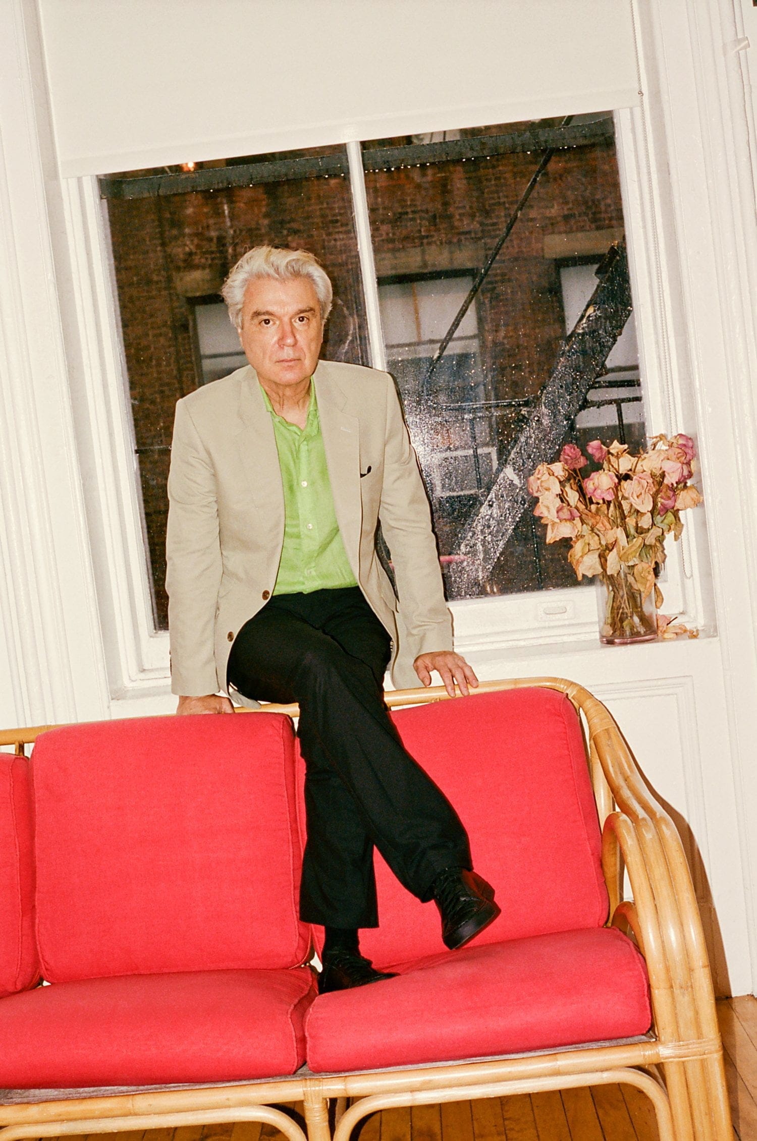 Byrne sitting on a red couch looking straight at the camera.